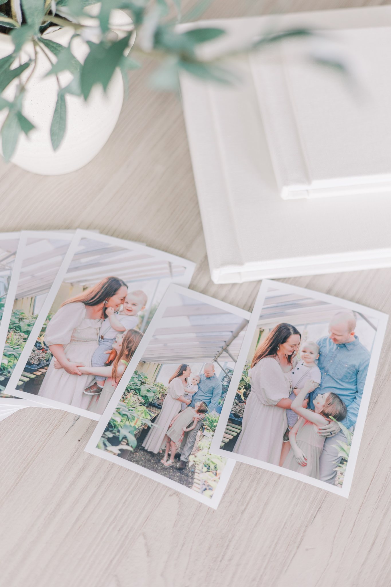 Augusta GA Family Photos - Printed portraits of a family are fanned out beside photo albums stacked on a table.