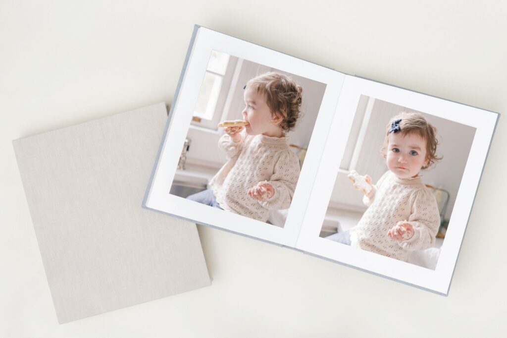 Augusta GA Family Photos - A photo album lays open displaying pictures of a girl in a kitchen enjoying a cookie. 