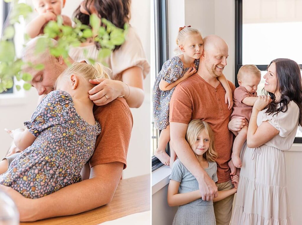 Martinez GA Family Photographer -Dad wraps arms around daughter and mom plays with daughter's hair. Family stands together near a window, and mom and dad share a moment smiling at one another.